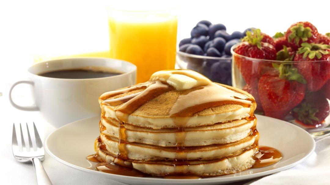 Stack of pancakes, coffee, strawberries, blueberries and orange juice