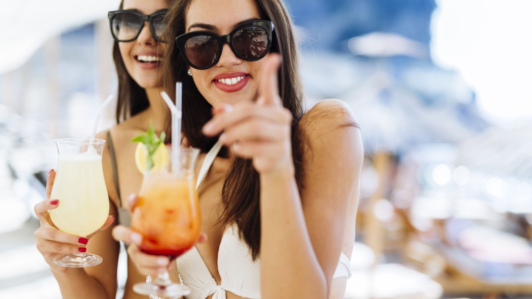 Two Women with Drinks Pointing at the camera at Crimson Pool