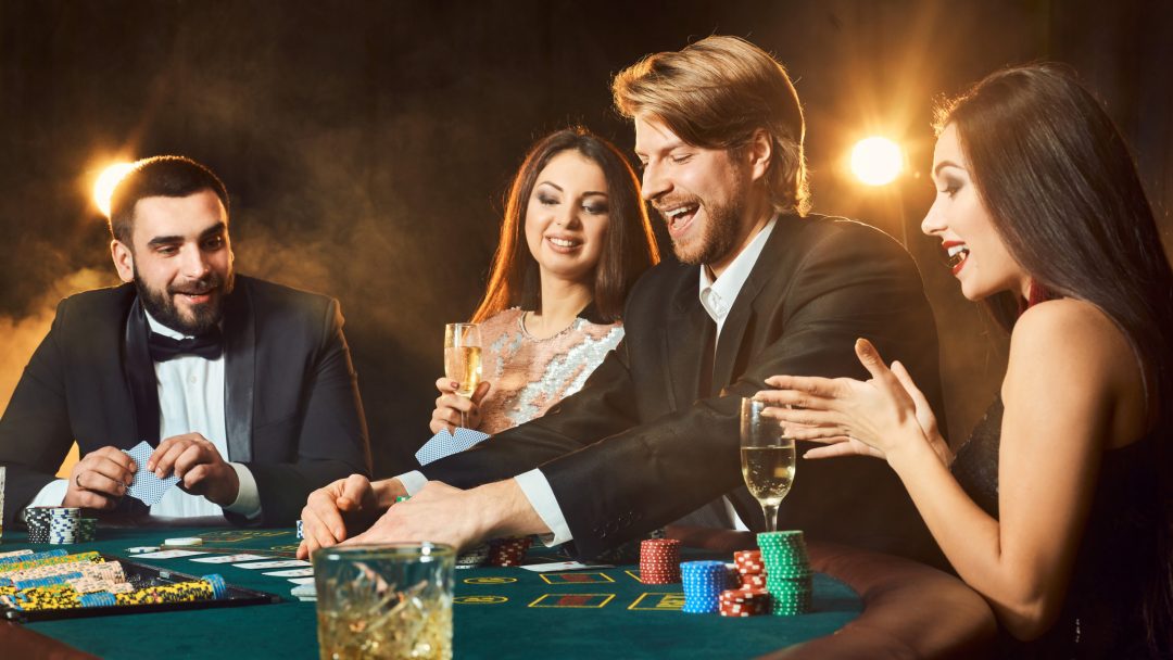 Four adults in dressy clothing playing cards at a table